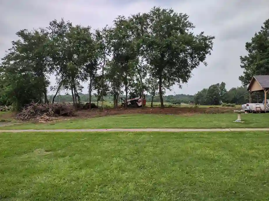 A cleared lot with brush piles along the treeline after Clear Cutters land clearing