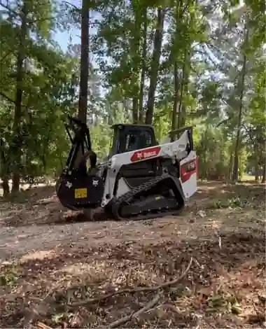 White Bobcat tracked loader clearing a lot