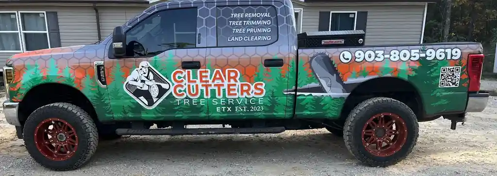 Side of the Clear Cutters F-250: pines over grey honeycomb plate with CLEAR CUTTERS in hi-vis orange
